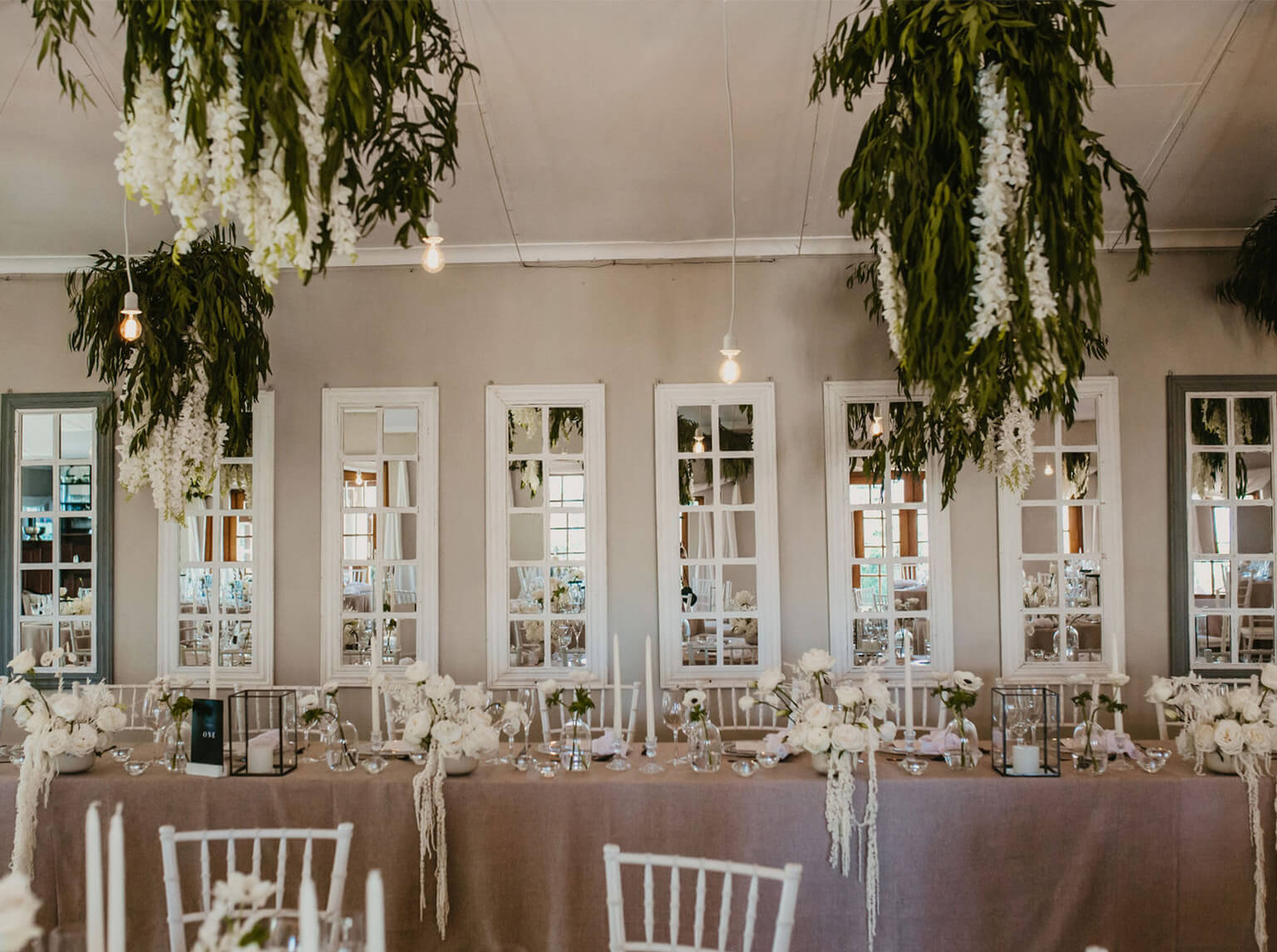 Reception hall set for dinner with hanging florals